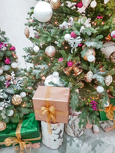 装饰金纸摄影照片_房间圣诞树附近的桦树桩上，用金纸包裹着漂亮的盒子，上面放着圣诞礼物