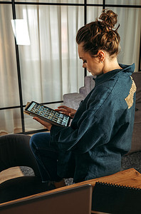 一位穿着深蓝色西装的年轻女子坐在沙发靠背上，手里拿着一台平板电脑。