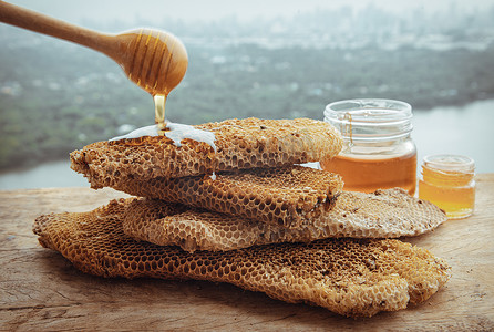 美味的蜂蜜从木制蜂蜜勺滴入新鲜的蜂窝中。