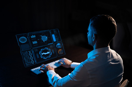 白人男子坐在虚拟屏幕前的黑暗中，在键盘上打字。
