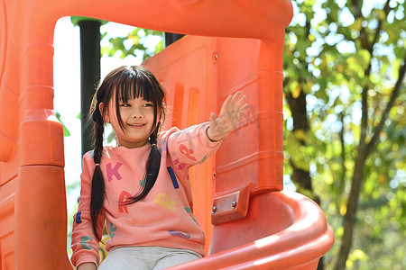 微笑的亚洲小女孩在户外操场上玩得开心。