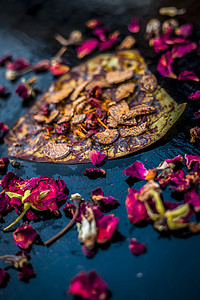 提水摄影照片_黑色表面上著名的印度传统马萨拉锅或 meetha 锅的特写，上面有一些玫瑰水，包括涂有 sauf、supari、甜味剂和一些椰子粉。
