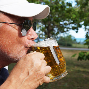 男人在大自然中用大玻璃杯喝啤酒