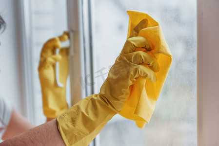 窗户泡沫摄影照片_黄色制服清洁窗户的主妇。