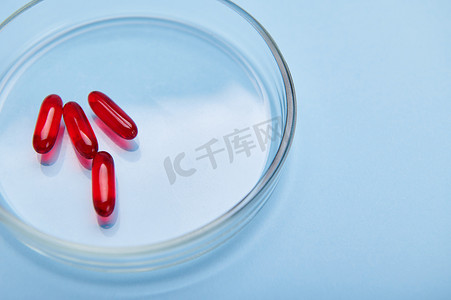 培养皿中含有脂溶性维生素 E、必需酸、Omega-3 或鱼油的红色明胶半透明胶囊。