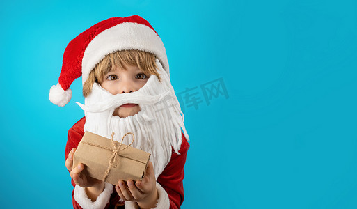 穿着圣诞老人服装的微笑男孩，带着胡须礼盒蝴蝶结。