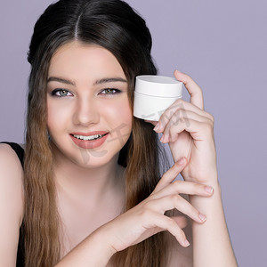 广告化妆女方脸摄影照片_年轻迷人的女孩拿着样机保湿护肤霜罐做广告。