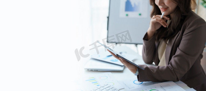 办公室内穿着黑色西装的女商人使用平板电脑，审计文书工作供客户联系，商务人士概念。