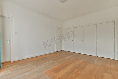 一间铺有木地板、白色墙壁和关闭的卧室