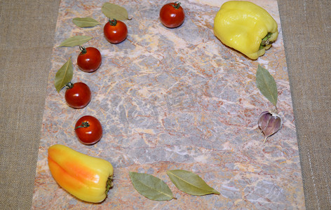 大理石表面上有自由空间的蔬菜：樱桃番茄、甜椒、大蒜和月桂叶