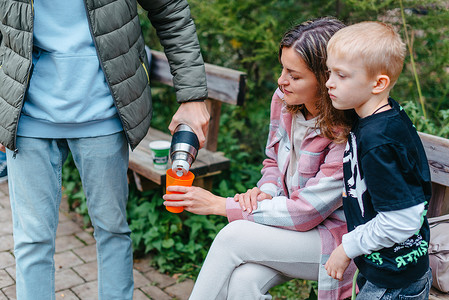 快乐的家庭在森林里用热水瓶喝茶。