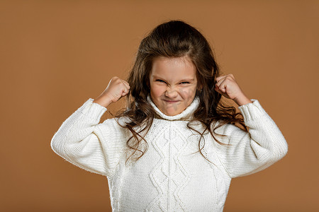 孩子生气摄影照片_穿着白色毛衣的愤怒尖叫的小女孩
