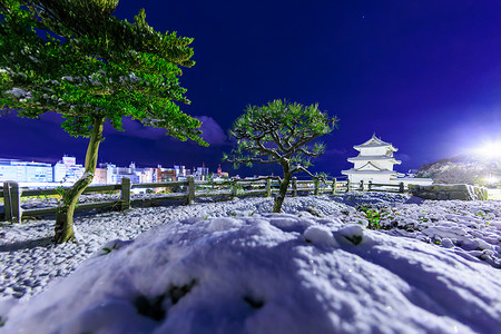 夜晚雪景摄影照片_白雪覆盖的风景，日本城堡和现代城市的夜晚