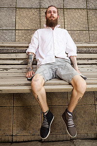 大胡子纹身时髦躺在长凳上