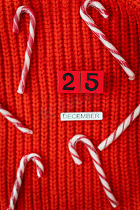 条纹和格子摄影照片_12 月 25 日，圣诞糖果连同木制字母和数字放在红色格子上。