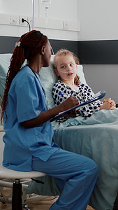 小孩讨论摄影照片_非裔美国儿科医生护士与生病的小孩讨论疾病症状