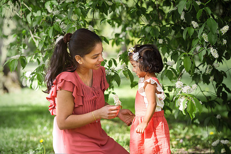 春天公园里一个穿红裙的快乐女人和两岁的女孩