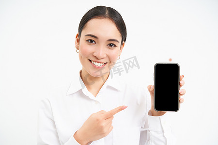 展示智能手机屏幕、指着手机微笑、推荐应用程序、站在白色背景上的女商人肖像