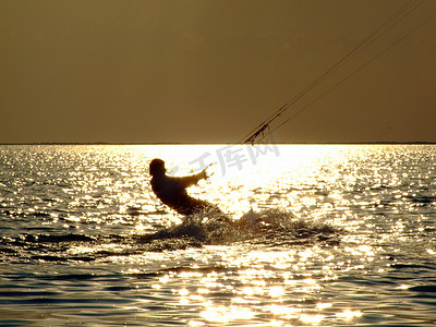 夕阳下海湾上的剪影风筝冲浪