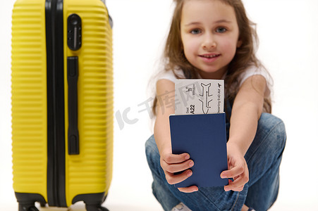 可爱详情摄影照片_详情：出国旅行的登机牌和身份证件在一个带着黄色手提箱的小女孩旅行者手中