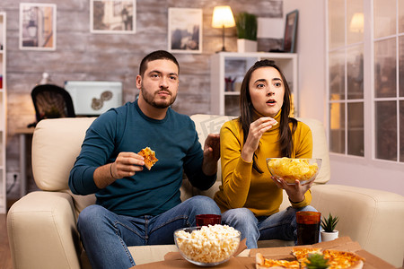 看电视吃快餐外卖的漂亮年轻夫妇