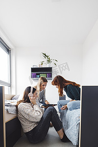 三名年轻女性的垂直照片，朋友们在宿舍共度时光