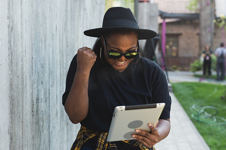 美丽的非洲裔美国女性使用数字平板电脑在户外看电影或谈论视频通话或社交网络。