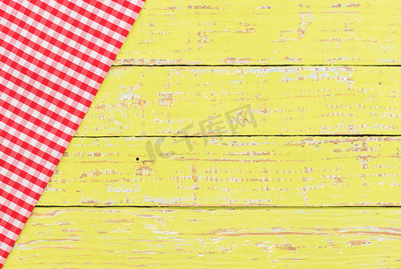 质朴的黄色桌子背景与红色格子桌布