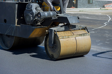 这是一种使用沥青专用设备进行重振压路机路面作业的沥青路面施工过程。