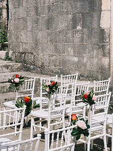 一排排白色花朵装饰的椅子靠在古色古香的石墙上