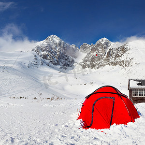 雪地上亮红色的攀岩帐篷，山上有 Lomnicky Stit 峰