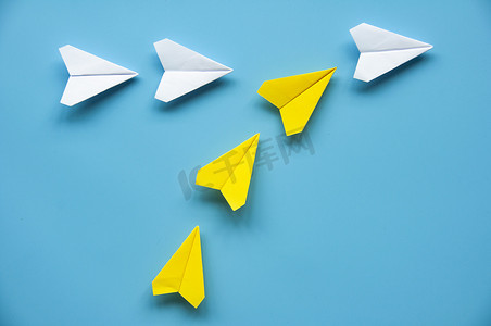 黄色纸飞机折纸在蓝色背景上加入其他白色飞机，带有可定制的文本或想法空间。