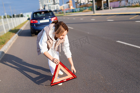由于道路上的汽车故障，一名女司机放置了一个三角形路标