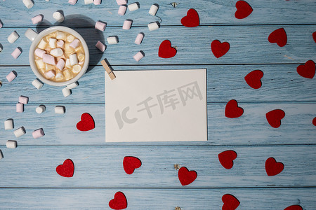 木制背景上用红心、白杯咖啡和棉花糖模拟的贺卡或邀请卡。