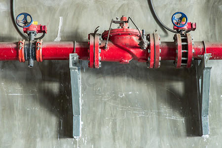 煤气管道摄影照片_混凝土墙上带门压阀的红水或煤气管道。