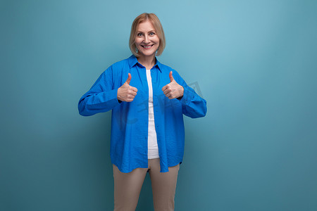 蓝色背景中一位身穿蓝色衬衫、带复制空间的快乐中年妇女的特写