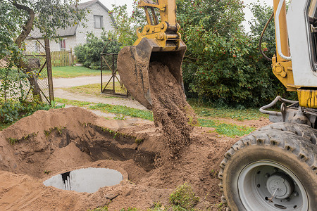 工业排污摄影照片_一桶带有一堆沙土的挖掘机在工业区埋下水道混凝土环