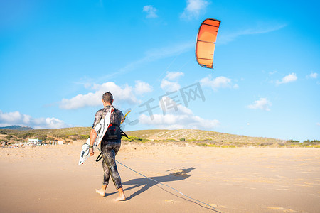 肖像波浪风筝冲浪者带着他的冲浪板和风筝在海滩散步