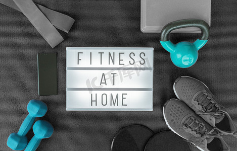 流行色谱摄影照片_在家健身力量训练计划，包括哑铃重量、阻力带，用于在运动垫上进行交叉健身锻炼。带黑灰色设备的灯箱标志的顶部视图