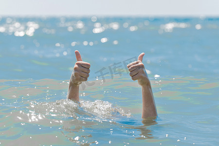 防溺水书摄影照片_溺水女孩从水下伸出的手竖起大拇指展示课堂。