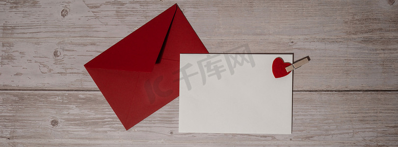 横幅问候语或邀请卡模拟与木制背景上的红色信封。