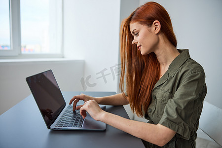 在明亮的办公室里全职工作的女性在笔记本电脑上打字时感到困惑