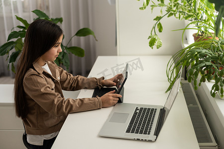 学校的少女学生戴着耳机在电脑屏幕上与在线老师进行远程学习。