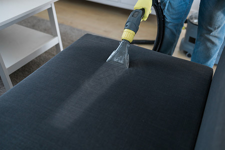 湿手套摄影照片_男士干洗店员工用专业提取方法将防护橡胶手套清洁沙发。
