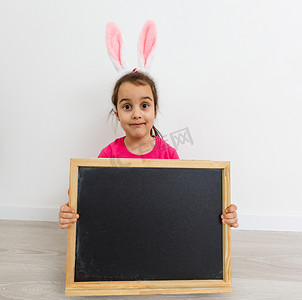 非常生气的小女孩戴着兔耳朵坐在家里的地板上