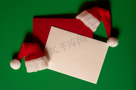 绿色背景上有空纸卡便条信封的圣诞老人帽子。