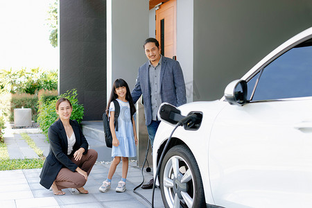 进步的年轻父母和女儿住在有电动汽车的家里。