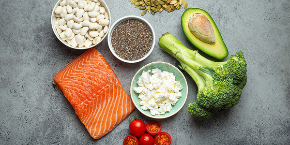 三文鱼摄影照片_如果一个人患有糖尿病，请选择健康食品：三文鱼、西兰花、鳄梨、豆类、蔬菜、灰色背景的种子。