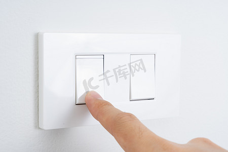打开电源摄影照片_在家里用白墙关闭手指打开或关闭白灯开关。