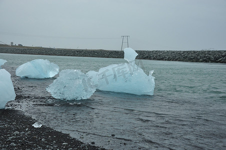 沙冰摄影照片_冰岛 Jokulsarlon 的 Fellsfjara 黑沙钻石海滩上晶莹剔透的冰块